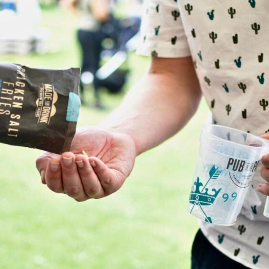 A pack of Made For Drink's Chicken Salt Fries being poured into a mans hand at Pub in the Park.